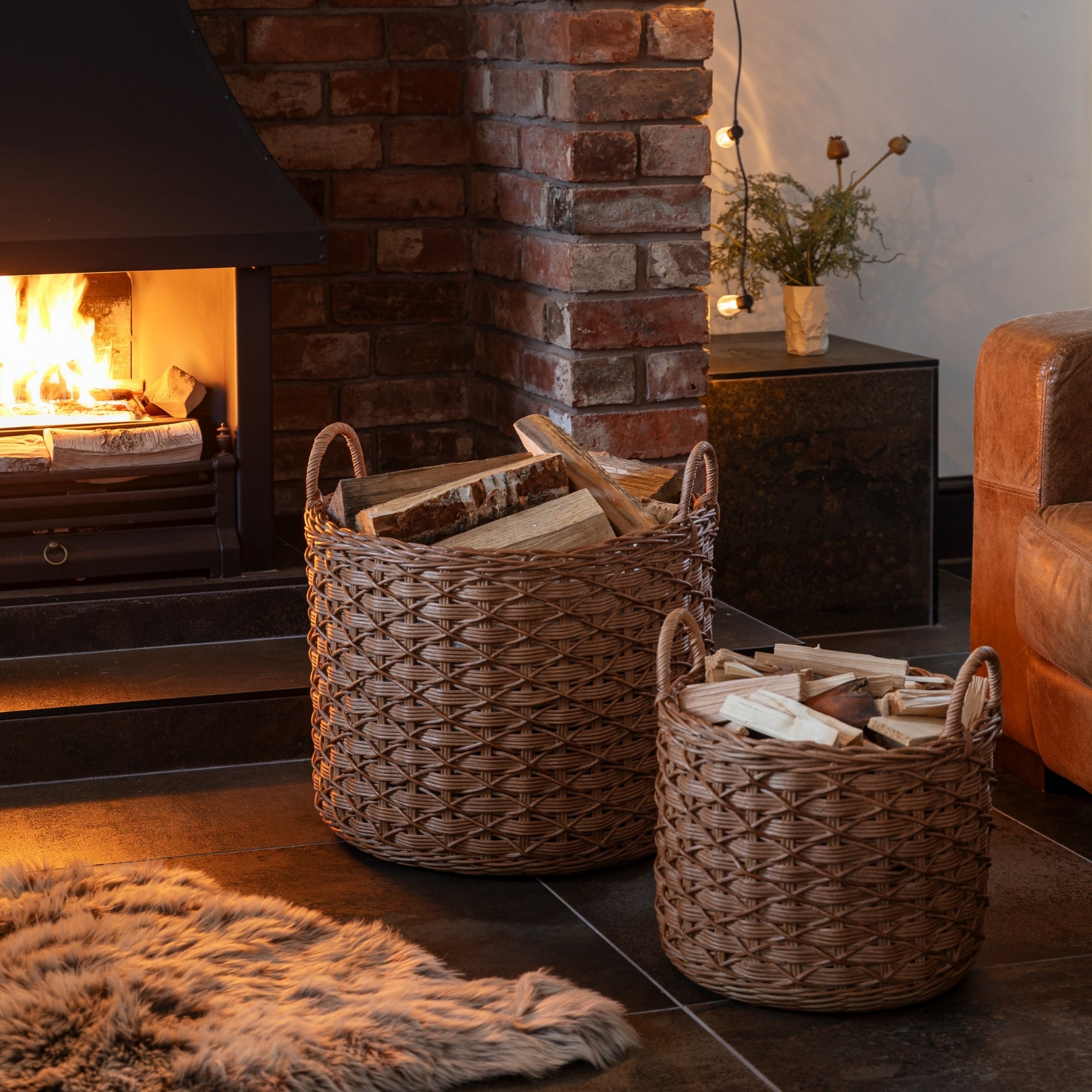 Two wicker baskets with firewood in front of a fireplace.