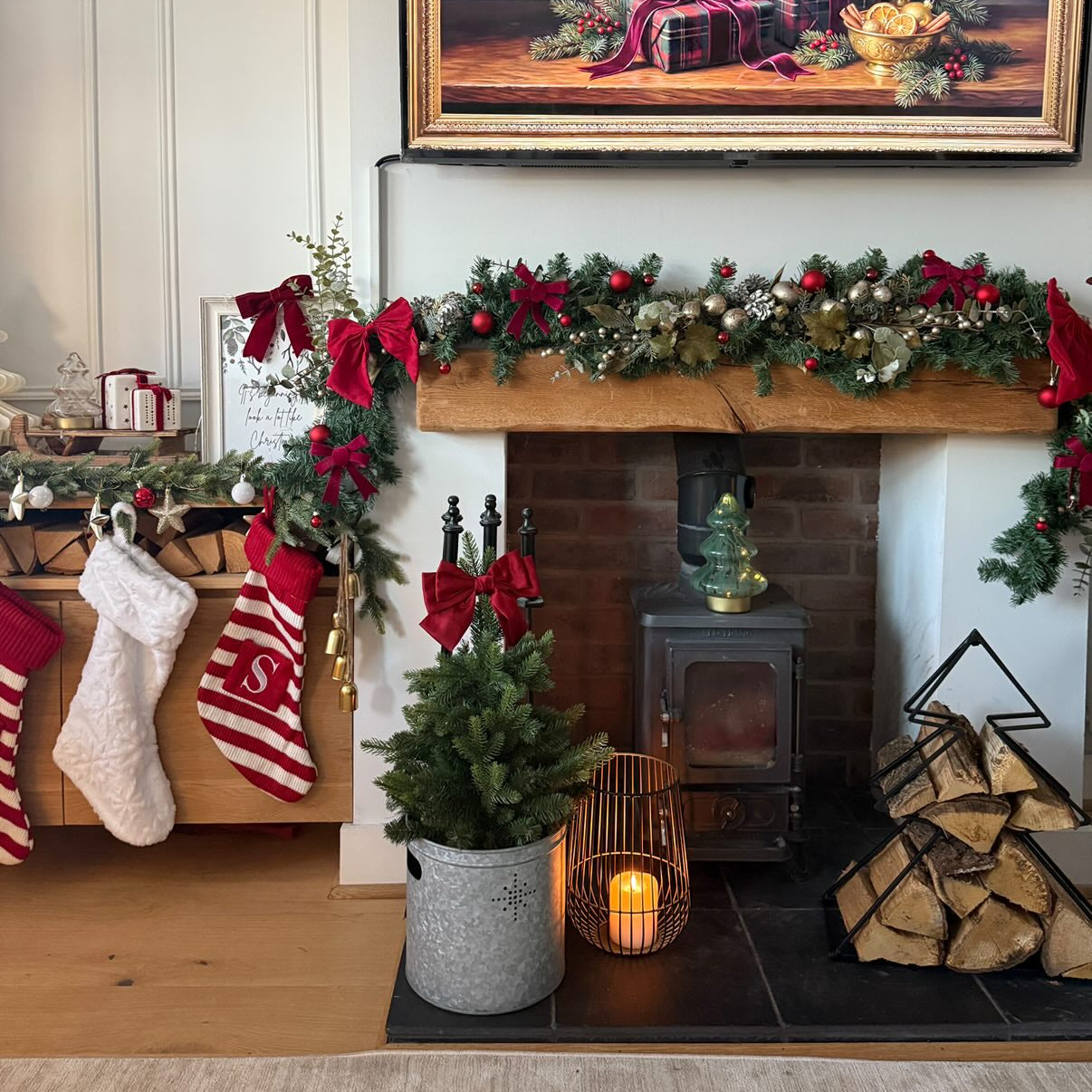 Cosy living room with Christmas decorations, including stockings, garlands, and a painting above a fireplace.